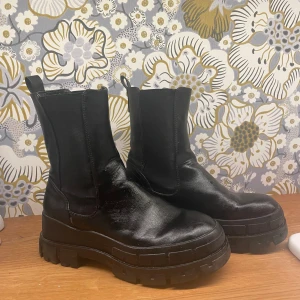 Svarta chunky Even & odd strl  - Säljer ett par svarta Even& oss  boots med chunky sula och rund tå. Skorna är i skinn och har elastiska paneler på sidorna för enkel påtagning. Perfekta för dig som vill ha en edgy och trendig look till höst och vinter.