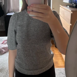 Grå stickad tröja från 157, S - Mysig grå stickad tröja från 157 med rund hals och puffade halvlånga ärmar. Tröjan har en enkel och stilren look som passar perfekt till jeans eller kjol. Materialet är mjukt och bekvämt, och modellen har en normal passform. säljs för inte kommer till användning, använd 2ggr