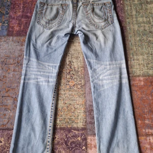 Feta True Religion Jeans - Riktig feta Trueys med en straight/Ricky passform och en liten washed stil. Använd några gången, köpt second hand. Midja 32 Total längd på 108cm. Liten stygn gått upp på sista bilden.