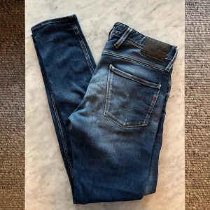 Blå Replay jeansbyxor, storlek 32/34 - Säljer ett par snygga blå jeans från Replay i klassisk tvätt. Modellen har raka ben och fem fickor med Replay-logga på bakfickan. Jeansen är tillverkade i slitstarkt denim och passar perfekt till en avslappnad stil.