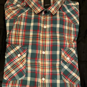 Rutig skjorta från Emilio, långärmad - Snygg rutig skjorta från Emilio i blått, rött, vitt och gult. Skjortan har klassisk krage, vita knappar framtill och två fickor med lock på bröstet. Långärmad modell i mjuk bomull, perfekt för dig som gillar färg och mönster.