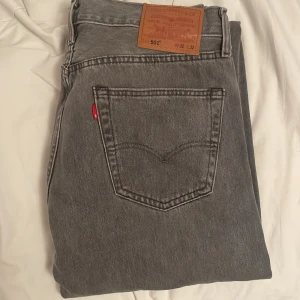 Grå Levi's 501 jeans W32 L32 - Snygga grå Levi's 501 jeans med klassisk rak passform och knäppning framtill. Jeansen har fem fickor, ikonisk röd Levi's-tagg och är tillverkade i slitstarkt bomullsjeans. Perfekta för dig som gillar en tidlös och clean look.