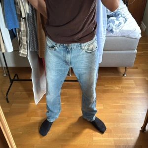 Ljusblå Nudie Jeans (W34 L34) - Säljer ett par ljusblå jeans från Nudie Jeans med klassisk femficksdesign och snygga kontrastsömmar på bakfickorna. Jeansen har rak passform och normal midja, tillverkade i bomull. Perfekta för dig som gillar en avslappnad och tidlös stil.