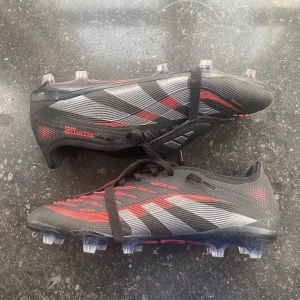 Adidas Predator PRO fotbollsskor svart/röd - Har bara används under en träning och en match.  Storlek 43 1/3. Pris kan diskuteras.
