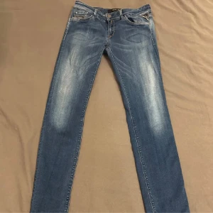  Replay Hyperflex jeans - Snygga blå skinny jeans från Replay med klassisk femficksdesign och slitningar framtill. Jeansen har ljus tvätt och detaljerade bakfickor med broderi samt Replay-logga på fickan. Perfekta för dig som gillar en tajt passform och stilren look.