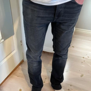 Nudie Jeans 31/30 thin fin - Snygga svarta blåa jeans från Nudie Jeans i modellen Thin Fin i mycket fint skick utan några defekter. Storleken enligt etiketten 31/32 men förkortade till ca 31/30 med bibehållen originalfåll. Längd 101cm. Midja 41cm. Ankel vidd 18,5.