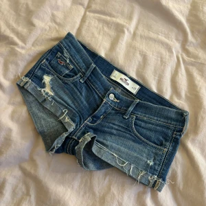 Blå jeansshorts från Hollister - Säljer ett par blå jeansshorts från Hollister med låg midja. Shortsen har slitna detaljer, fransiga kanter och klassiska fickor både fram och bak. Har ingen bild med de på tyvärr!💘