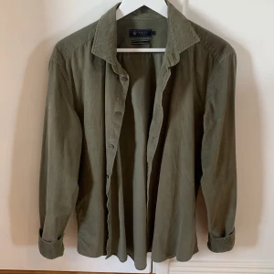 Olivgrön skjorta från Riley slim fit - Olivgrön skjorta från Riley i slim fit-modell. Skjortan har klassisk krage, långa ärmar och knäppning framtill. Tillverkad i mjuk bomull, perfekt för en clean och stilren look.