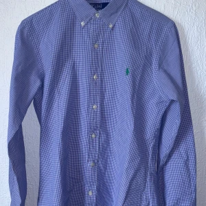 Polo Ralph Lauren skjorta - Blå rutig skjorta polo by ralph lauren skjorta i storlek s - slim fit med grön broderad logga på bröstet.   Nyskick, helt ny oanvänd skjorta   pris: 479kr
