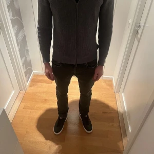 Nudie Jeans lean dean - Säljer ett par svarta jeans från Nudie Jeans med klassisk femficksdesign och diskret broderi på bakfickorna. Jeansen har en rak passform och är tillverkade i mjukt denimtyg. Perfekta för dig som gillar en stilren och enkel look. 