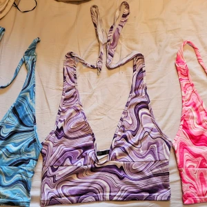 Lila swirl halterneck topp från SHEIN - Trendig lila och vit swirlmönstrad halterneck topp från SHEIN. Djup v-ringning och knyt i nacken, croppad modell med bred resår under bysten. Perfekt för dig som gillar färg och coola mönster. Materialet är mjukt och stretchigt, troligtvis polyester. Inte använda så mycket