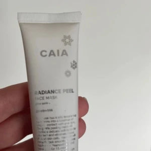 CAIA Radiance Peel Face Mask - Limited edition Radiance Peel Face Mask från CAIA i en vit tub med silvriga snöflingor. Masken innehåller AHA-syra och har en geléliknande konsistens som förvandlas till olja vid applicering. Perfekt för dig som vill boosta glow och fräschör i huden.