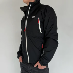 Helly Hansen Jacka - Vi säljer nu denna stilrena Jacka i märket Helly Hansen! Jacka är i storleken M, modellen på bilden är 180cm 75kg! Västen är i gott skick utan några defekter. Skriv gärna vid frågor och funderingar!