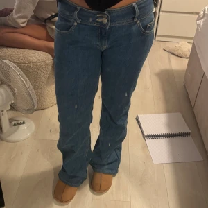 Low waist jeans  - Säljer ett par klassiska blå jeans från Tommy Jeans med bootcut passform. Jeansen har hög midja, raka ben med lätt utsvängning och tydliga sömmar. Stort Tommy Jeans-märke bak i midjan och femficksmodell. Perfekta för en avslappnad och trendig look.
