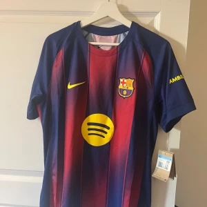 FC Barcelona Nike matchtröja M - FC Barcelona matchtröja från Nike i Dri-FIT-material. Klassisk design med blå och röda vertikala ränder, gula detaljer och klubbmärke på bröstet. Spotify-logga framtill och UNHCR-tryck bak. Nypris 1149 kronor.