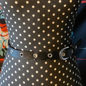 Svart bälte med nitar  -  svart bälte i fejk skinn med typ nitar längs hela bandet. Sitter simpelt. Lite slitet så aa. Ish 100 cm. Vet inte kan mäta om det är viktigt men det är rätt litet 