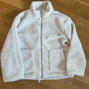 Beige teddyjacka med dragkedja - Mysig beige teddyjacka med hög krage och två stora fickor framtill. Jackan är sparsamt använd och därför som ny😊