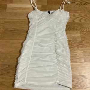 Vit kort klänning Mossimo by Ivana - Supersnygg vit kort klänning från Mossimo by Ivana med smala axelband och rynkade detaljer längs sidorna. Klänningen är figurnära och har ett tunt mesh-tyg över ett fodrat lager. Köpt utomlands och använd två gånger. Supersöt och snygg på. Priset kan diskuteras 😊