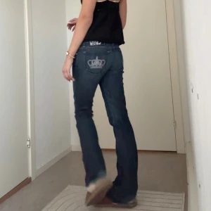 Victoria Beckham bootcut jeans - Snygga blå jeans från Rock & Republic/ Victoria Beckham med bootcut passform och låg midja. Jeansen har coola detaljer som krona i silver på bakfickan och på knappen, samt klassisk femficksdesign. Materialet är jeans med en mörk tvätt, är i mycket bra skick jag har bara använt dem ett fåtal gånger, det är dock slitningar längst ner vid hälen då dom är lite långa på mig som är 167 cm, priset kan diskuteras vid snabb affär 