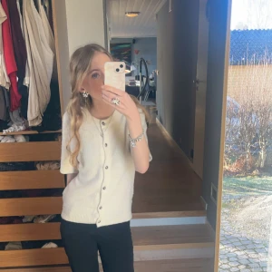 Beige kofta med kort ärm och knappar - Superfin beige kofta med korta ärmar och knäppning framtill. Enkel och stilren design med ribbad nederkant. Perfekt att slänga på sig över ett linne eller t-shirt. Passar till både jeans och kjol för en chill look. Lite lite nopprig. 