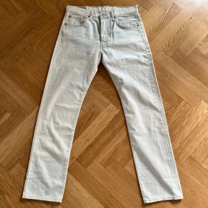 Levi's 501 vita jeans W31 L32 - Säljer ett par klassiska Levi's 501 jeans i vit färg. De har rak passform, fem fickor och knappgylf. Jeansen är tillverkade i bomull och har en stilren look som funkar till många outfits. Perfekta om du vill ha ett par ljusa jeans med ikonisk känsla. Inga defekter, hör av er vid frågor
