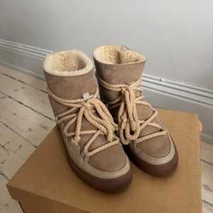 Beige Inuikii boots med ullfoder - Säljer ett par snygga beige boots från Inuikii med mjukt ullfoder och grova snören. Skorna har en mix av mocka och skinn, platt sula och rund tå. Perfekta för kalla dagar och ger en cool vinterlook. Nypris ca 2700kr och endast andvända 2-3 ggr. Box och alla tillbehör tillkommer 