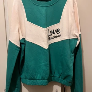 Love Moschino strl 42 - weatshirt i storlek UK 14 (motsvarar strl 42).  Helt ny, endast provad. Material: 100% bomull  Se mina andra annonser då jag även säljer byxorna som hör till.  Nypris: 2 174kr  