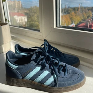 Adidas Spezial sneakers blå  - Säljer ett par Adidas Spezial sneakers i mörkblå mocka med ljusblå ränder och detaljer. Klassisk retrostil med snörning och gummisula. Perfekta för dig som gillar streetwear och vill ha en ikonisk look. Adidaslogga i guld på sidan.