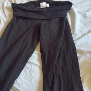 Svarta yoga pants från Gina Tricot - Svarta leggings från Gina Tricot med hög midja och bred linning. Mjukt och stretchigt material som sitter skönt på kroppen. Perfekta för en chill och avslappnad stil. Passar dig som gillar enkel och stilren look.