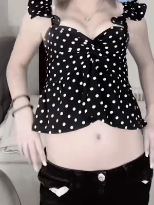 Prickig blus med rosett och volang - Supersöt blus i mörkblått med vita prickar, knytrosett framtill och volangdetaljer vid axelbanden. Blusen är croppad och har en luftig passform med axelbandslös känsla. Perfekt för sommarens alla tillfällen!