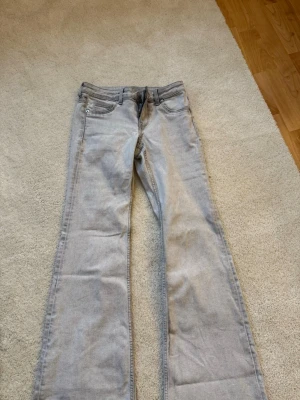 Ljusgrå bootcut jeans - Säljer ett par ljusgrå jeans med bootcut passform. Jeansen har klassisk femficksdesign, normal midja och är tillverkade i mjukt denimtyg. Perfekta om du gillar en avslappnad men ändå snygg look.