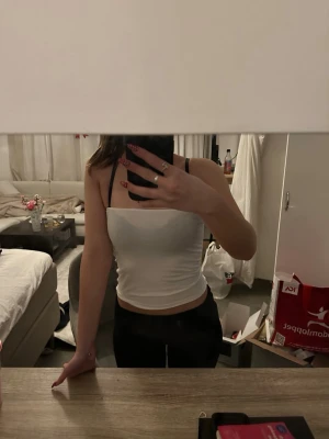 Vit croppad tubtopp - Säljer en enkel och stilren vit croppad tubtopp. Toppen är ärmlös och har en rak, tight passform som sitter snyggt mot kroppen. Perfekt till sommaren och lätt att matcha med olika outfits.