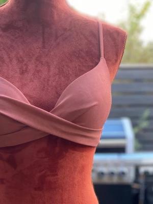 NLY Beach rostfärgad bikiniöverdel, storlek 70C - Rostfärgad bikiniöverdel med smala axelband och en dekorativ knut framtill. Spänne baktill för enkel justering. 85% polyester, 15% elastan  Inga bilder när den sitter på mig! Katter finns i hemmet!