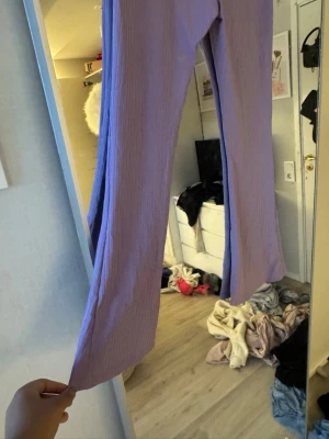  Lila utsvängda byxor -  Säljer ett par lila utsvängda byxor som är en ribbade och har tyget likt yoga pants
