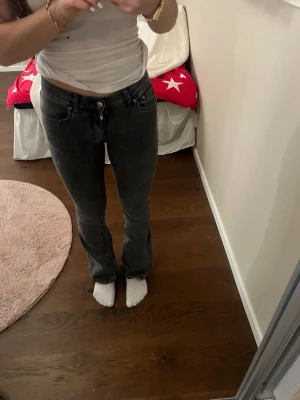 mörk gråa bootcut jeans  - Säljer ett par mörk gråa  bootcut jeans. Jeansen har klassisk femficksdesign, normal passform och är tillverkade i jeansmaterial. Snyggt utsvängda ben och låg midja.