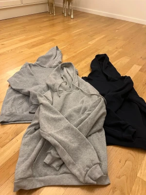 Tre hoodies i olika färger - En mörkblå i strl L en grå med snöregn i strl M och en till grå i strl M