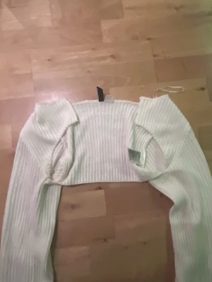 Vit croppad ribbad tröja Divided - Säljer en vit croppad tröja från Divided i storlek XS. Tröjan är ribbstickad med lång ärm och har en tight passform. Perfekt för lager-på-lager och snygg till både jeans och kjol.