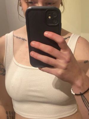 Vit ribbad linnetopp från H&M - Säljer en enkel och stilren vit ribbad linnetopp från H&M i storlek S. Toppen är ärmlös med breda axelband och croppad passform, perfekt till jeans eller kjol. Materialet är mjukt och stretchigt för en bekväm känsla.