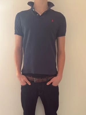 Mörkblå pikétröja Polo Ralph Lauren (Bundle) - Säljer en mörkblå pikétröja från Polo Ralph Lauren i slim fit-modell. Pikén är i grymt skick! Modellen på bilden är c.a 180cm!Pikén är i storleken 14-16 år men passar även dig som har XS. Tveka inte på att höra av er vid minsta fundering