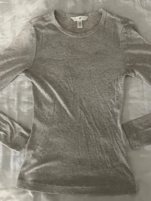 Ljusbeige långärmad topp  - En enkel och stilren ljusbeige långärmad topp från H&M. Modellen är figurnära med mjukt och stretchigt material. Toppen ska efterlikna en intimissimi topp då den är lite see through. 