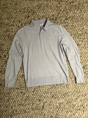 Ljusblå stickad pikétröja Filippa K - Säljer en ljusblå stickad pikétröja från Filippa K i storlek S. Tröjan har klassisk krage, knäppning med två knappar och är långärmad. Tillverkad i mjuk ullblandning (58% RWS ull) som känns riktigt skön mot huden. Perfekt för dig som gillar stilrena och tidlösa plagg.