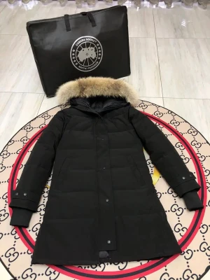 Svart dunjacka med päls från Canada Goose - Säljer en svart lång dunjacka från Canada Goose med fluffig päls på huvan. Jackan har quiltad design, långa ärmar med ribbade muddar och knappar vid ärmslut. Perfekt för kalla vinterdagar och har en stilren look som funkar till allt, den är även helt ny har aldrig använts!! 