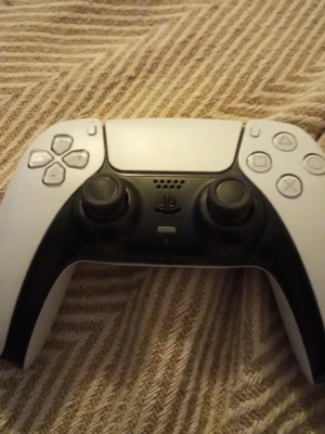 PlayStation 5 DualSense Wireless Controller - DualSense trådlös handkontroll till PlayStation 5 i vitt och svart. Ergonomisk design, adaptiva triggers och inbyggd mikrofon. Kontrollen ser ut att vara i gott skick utan synliga skador eller större slitage.