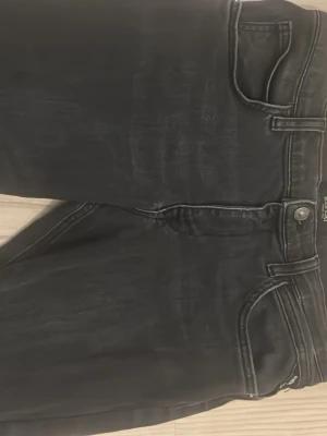 Svarta Replay Anbass jeans slim fit - Säljer ett par svarta Replay Anbass jeans med slim fit. Klassisk femficksmodell med snygga slitningar och detaljerade sömmar. Jeansen har normal midja och raka ben, tillverkade i stretchig bomullsblandning för skön passform.