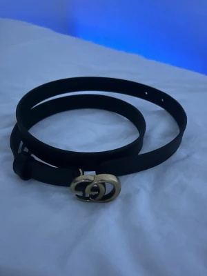 Svart Gucci bälte med GG-spänne ( Oanvänt )  - Säljer ett svart bälte från Gucci med det klassiska dubbla GG-spännet i guld. Bältet är gjort i slätt skinn och kommer i originalbox med dustbag och kvitto. Perfekt accessoar för att lyfta vilken outfit som helst. Öppen för förhandling!  Nypris : 2800kr