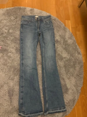 Blå bootcut jeans från Gina Tricot - Snygga blå jeans från Gina Tricot i storlek 164. Modellen har bootcut-ben och klassisk femficksdesign med broderad bakficka. Jeansen är i ett mjukt denimtyg och har en normal passform med medelhög midja.
