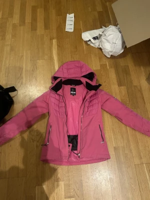 Rosa vinterjacka från 8848 Altitude - Säljer en snygg rosa vinterjacka från 8848 Altitude med huva och dragkedjor framtill. Jackan har quiltade partier upptill och på ärmarna, samt praktiska fickor med dragkedja. Perfekt för kalla dagar och riktigt skön att ha på sig.