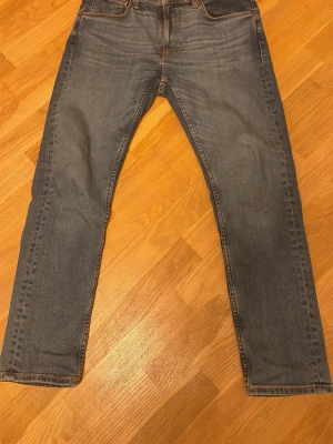 Nudie Jeans Lean Dean Lost Orange - Säljer ett par blå Lean Dean Lost Orange jeans från Nudie Jeans. Klassisk femficksmodell med orange sömmar och broderade bakfickor. Tillverkade i 99% bomull och 1% elastan för lite stretch. Snygg tvätt och rak passform.
