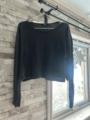 Svart croppad långärmad topp Bik Bok - En enkel svart långärmad topp från Bik Bok med croppad passform. Tillverkad i mjuk bomull och har en rund halsringning. Perfekt att styla med höga jeans eller kjol för en chill look.