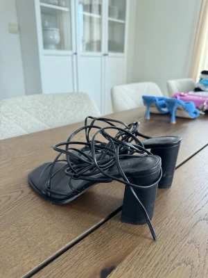 Svarta klackskor med snörning - Svarta klackskor från ASPS med tunna remmar som snöras runt foten. Bred passform. Använda 2 gånger.